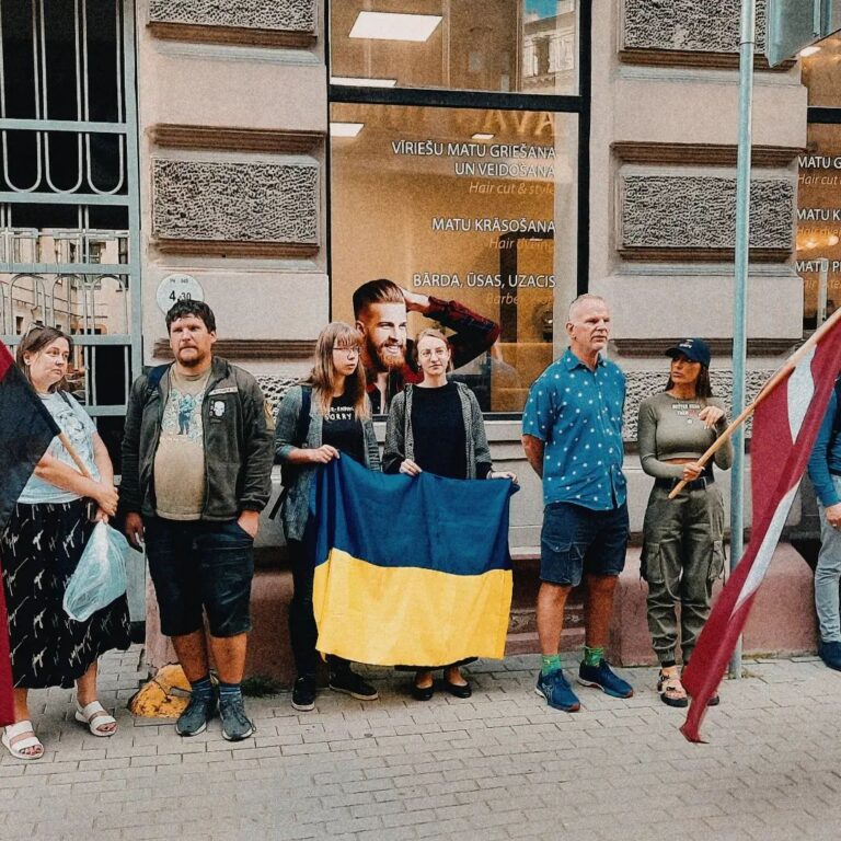 Meitenes tur Ukrainas un Latvijas karogus piketā